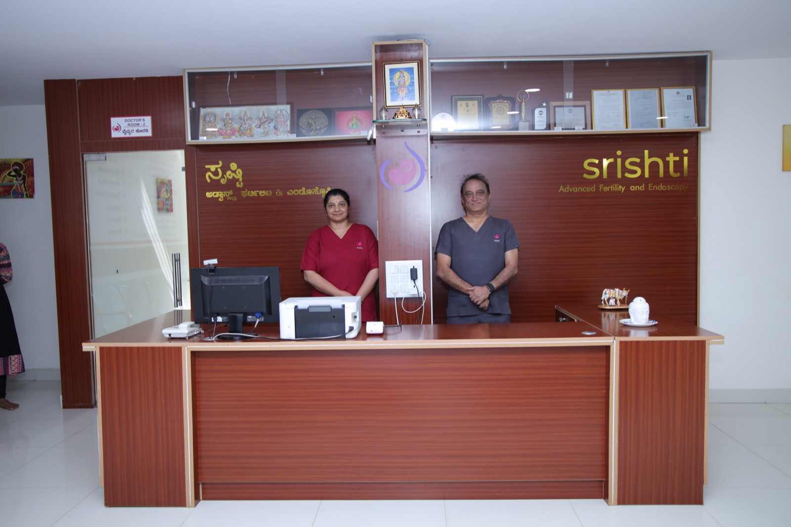Reception staff at Srishti SAFE clinic in front of the brand wall, Hubli